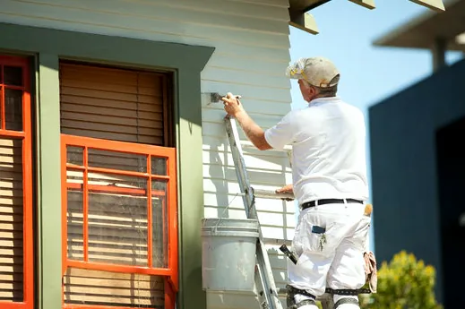 Painter brushing siding and trim on a Gardena home