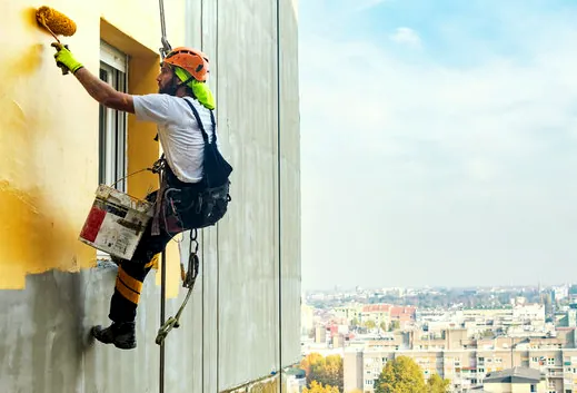 Painter on rope access working on a tall commercial wall near Gardena